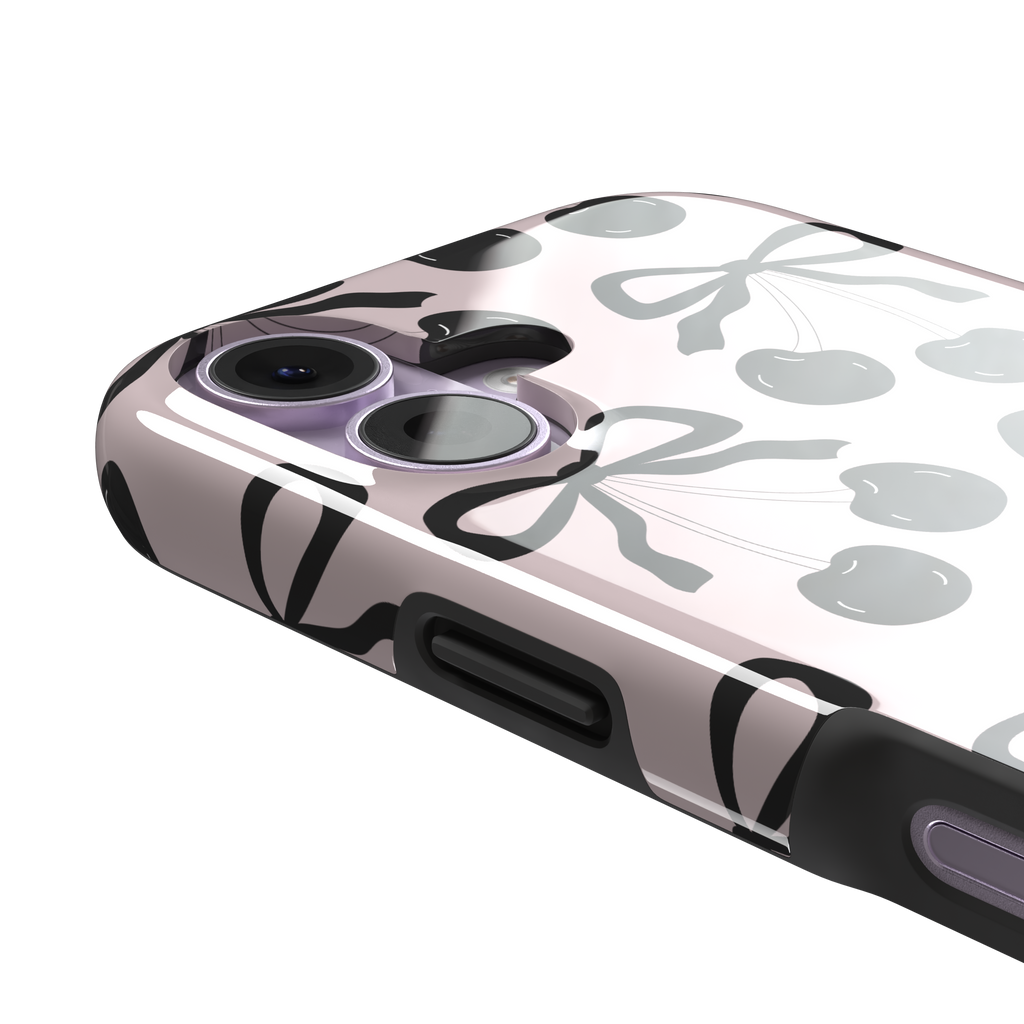 Black Cherry phone case with an all-over pattern of black cherries and ribbon bows on a blush pink background, phone case by Caselier — tough case, volume buttons detail