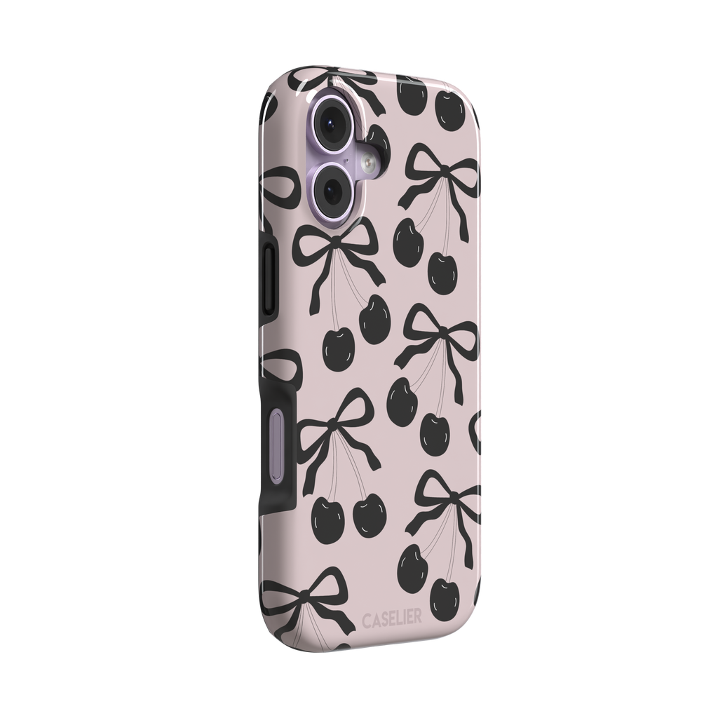 Black Cherry phone case with an all-over pattern of black cherries and ribbon bows on a blush pink background, phone case by Caselier — tough case, left view