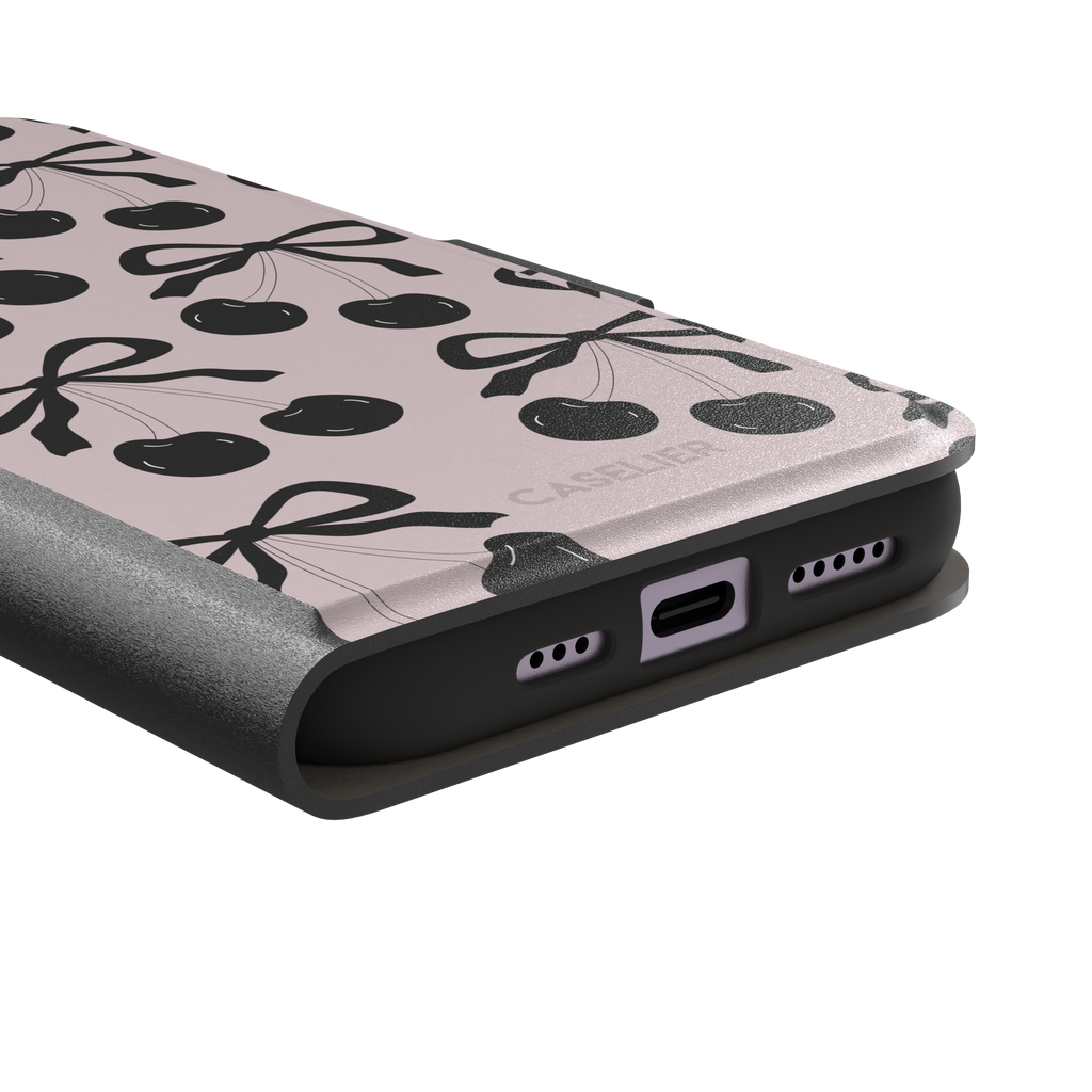 Black Cherry phone case with an all-over pattern of black cherries and ribbon bows on a blush pink background, phone case by Caselier — wallet case, charging port detail