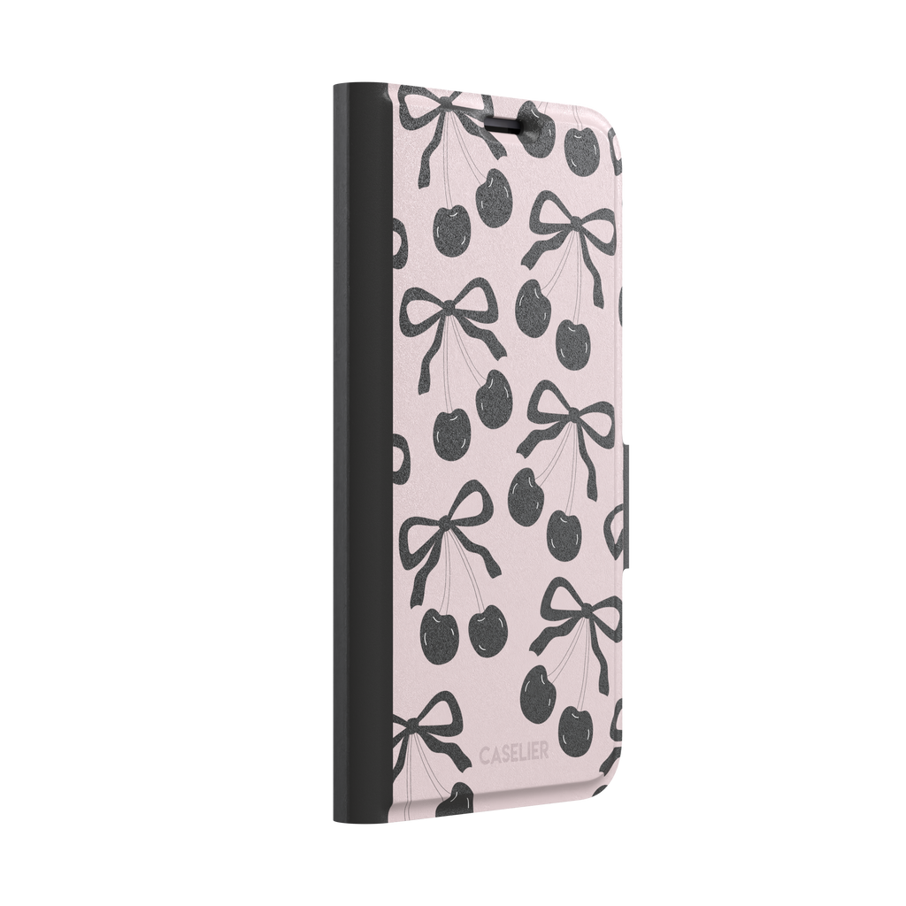 Black Cherry phone case with an all-over pattern of black cherries and ribbon bows on a blush pink background, phone case by Caselier — wallet case, left view