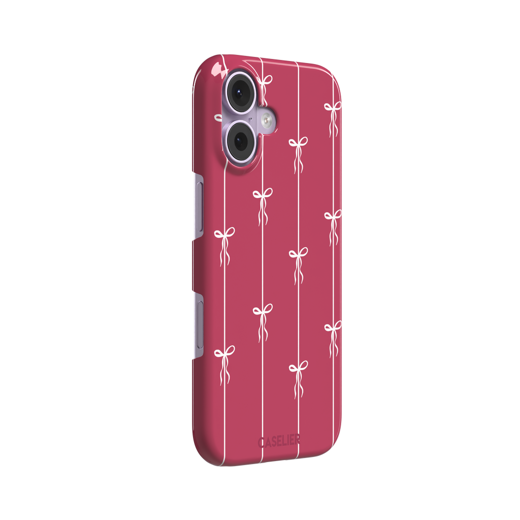 Bows on String phone case in raspberry pink with white ribbon bows tied along vertical stripes, phone case by Caselier — snap case, left view