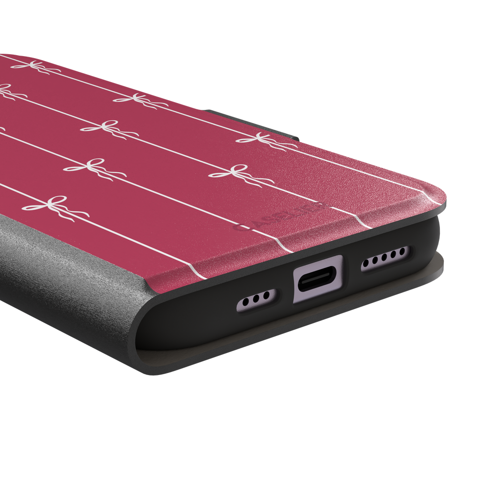 Bows on String phone case in raspberry pink with white ribbon bows tied along vertical stripes, phone case by Caselier — wallet case, charging port detail