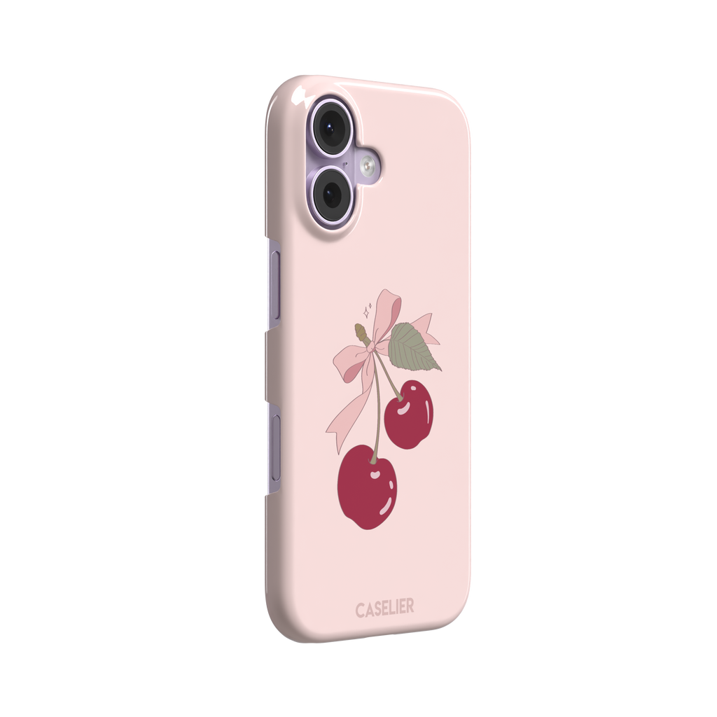 Soft pink phone case featuring two glossy red cherries tied with a pink ribbon bow and green leaf illustration in a coquette style, phone case by Caselier — snap case, left view