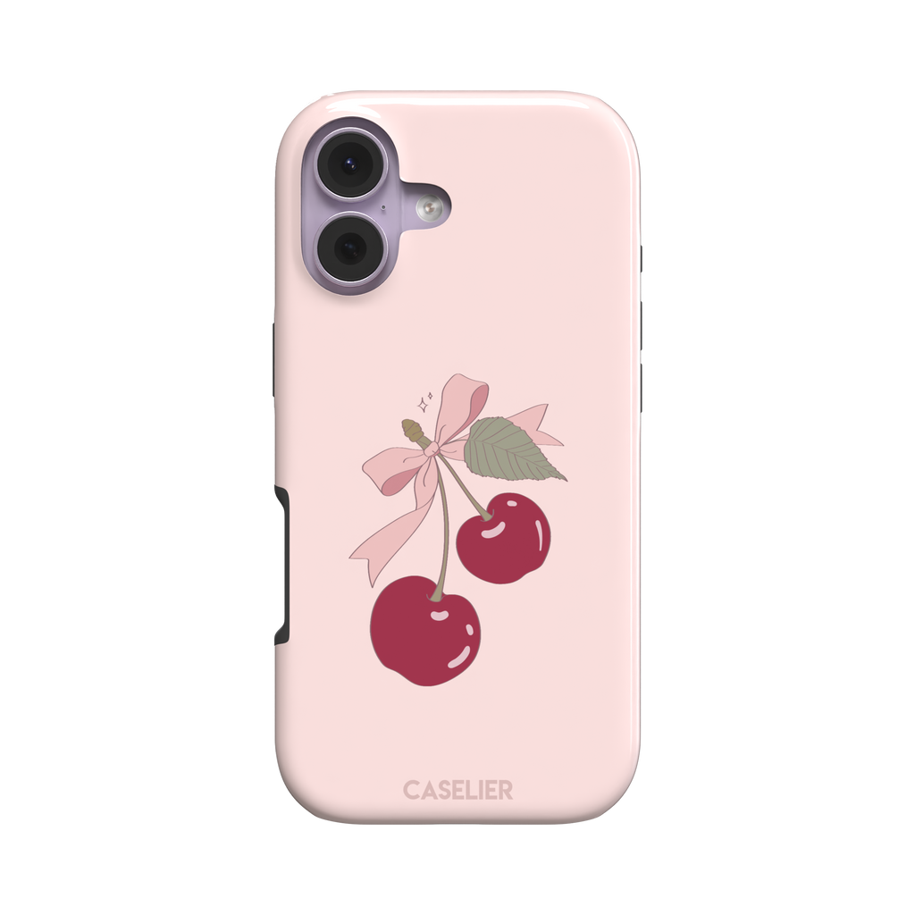 Soft pink phone case featuring two glossy red cherries tied with a pink ribbon bow and green leaf illustration in a coquette style, phone case by Caselier — tough case, front view
