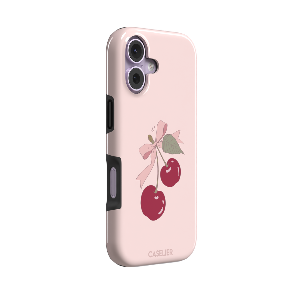 Soft pink phone case featuring two glossy red cherries tied with a pink ribbon bow and green leaf illustration in a coquette style, phone case by Caselier — tough case, left view