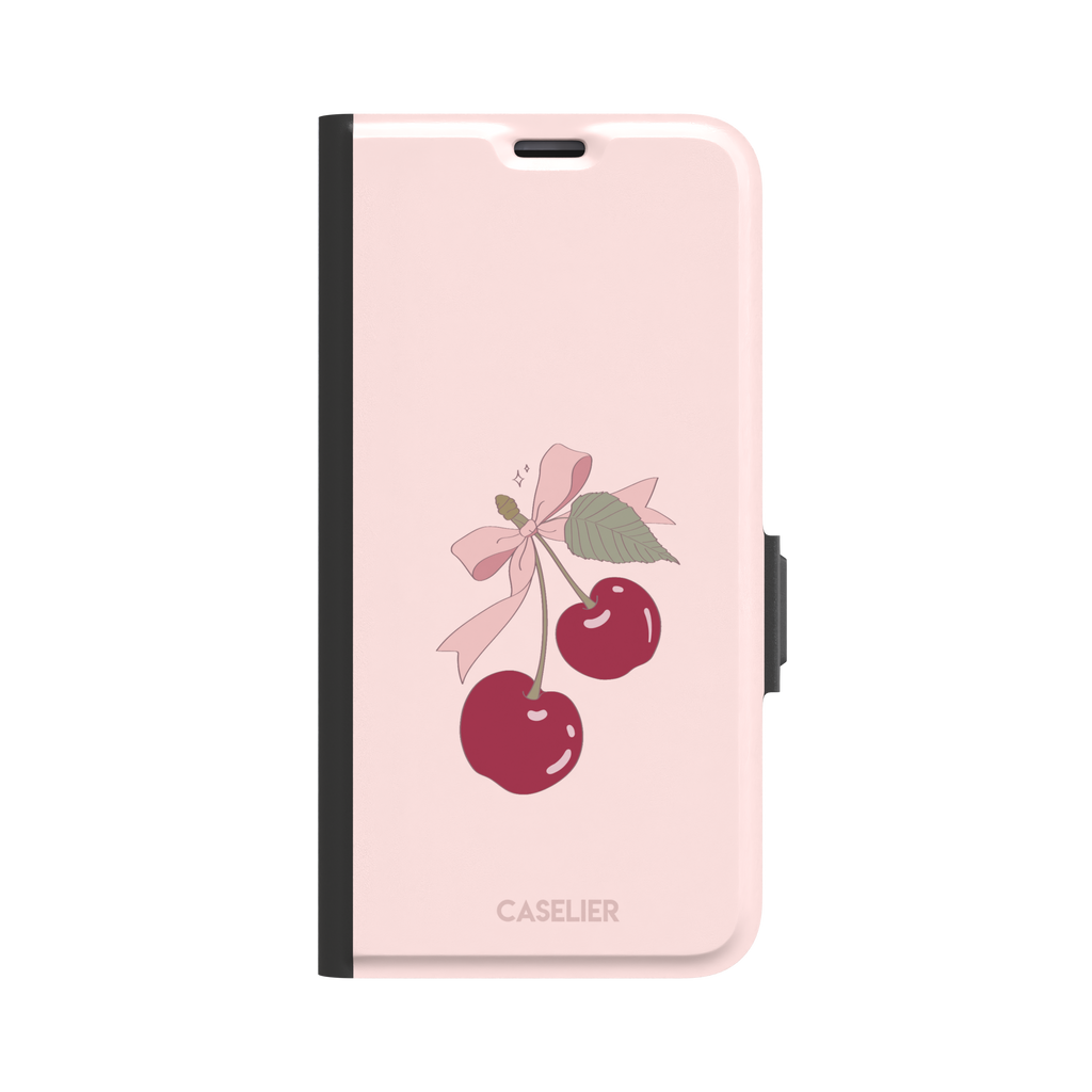 Soft pink phone case featuring two glossy red cherries tied with a pink ribbon bow and green leaf illustration in a coquette style, phone case by Caselier — wallet case, front view
