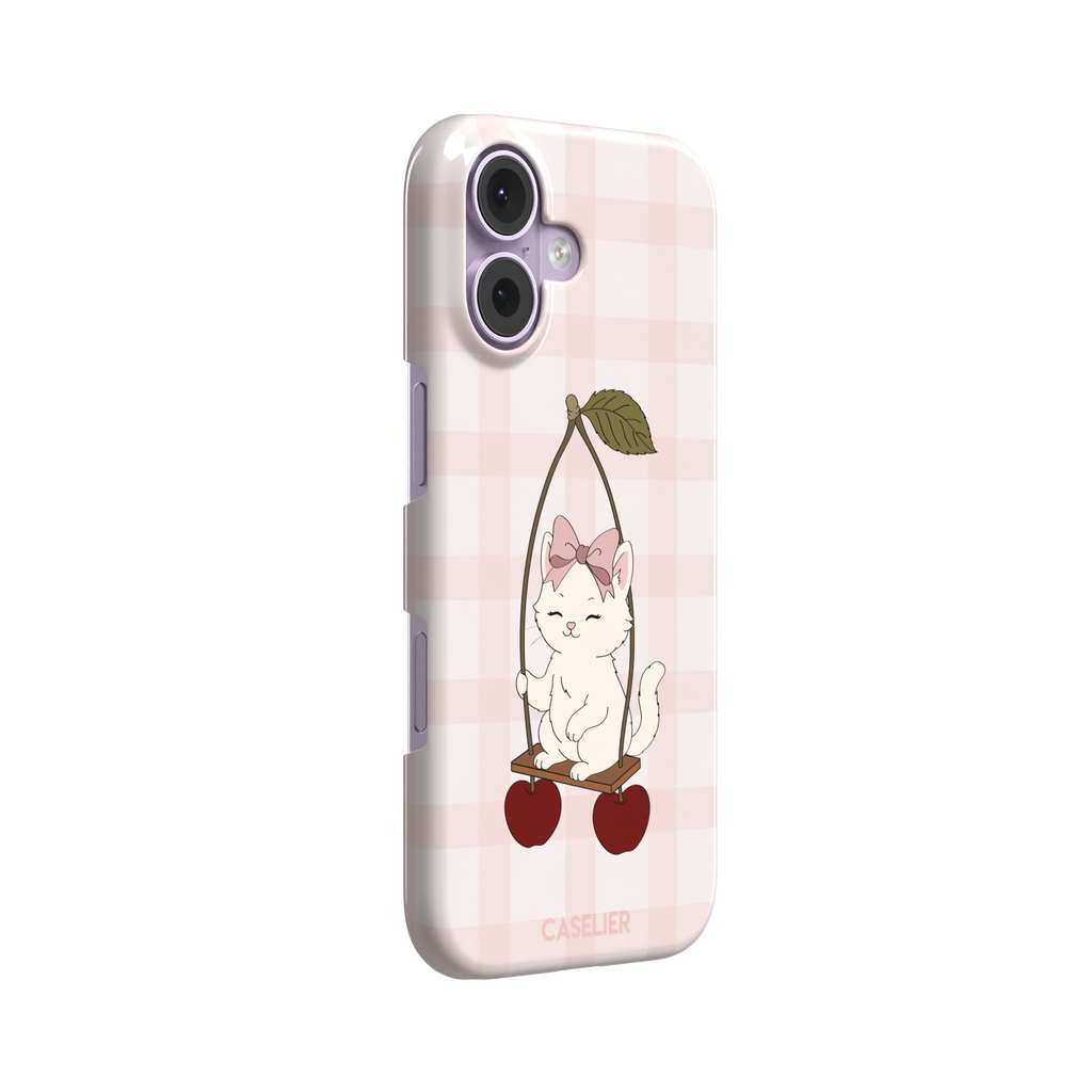 Cherry Swing phone case featuring a white cartoon kitten with a pink bow sitting on a cherry-suspended swing over a blush pink gingham background, phone case by Caselier — snap case, left view