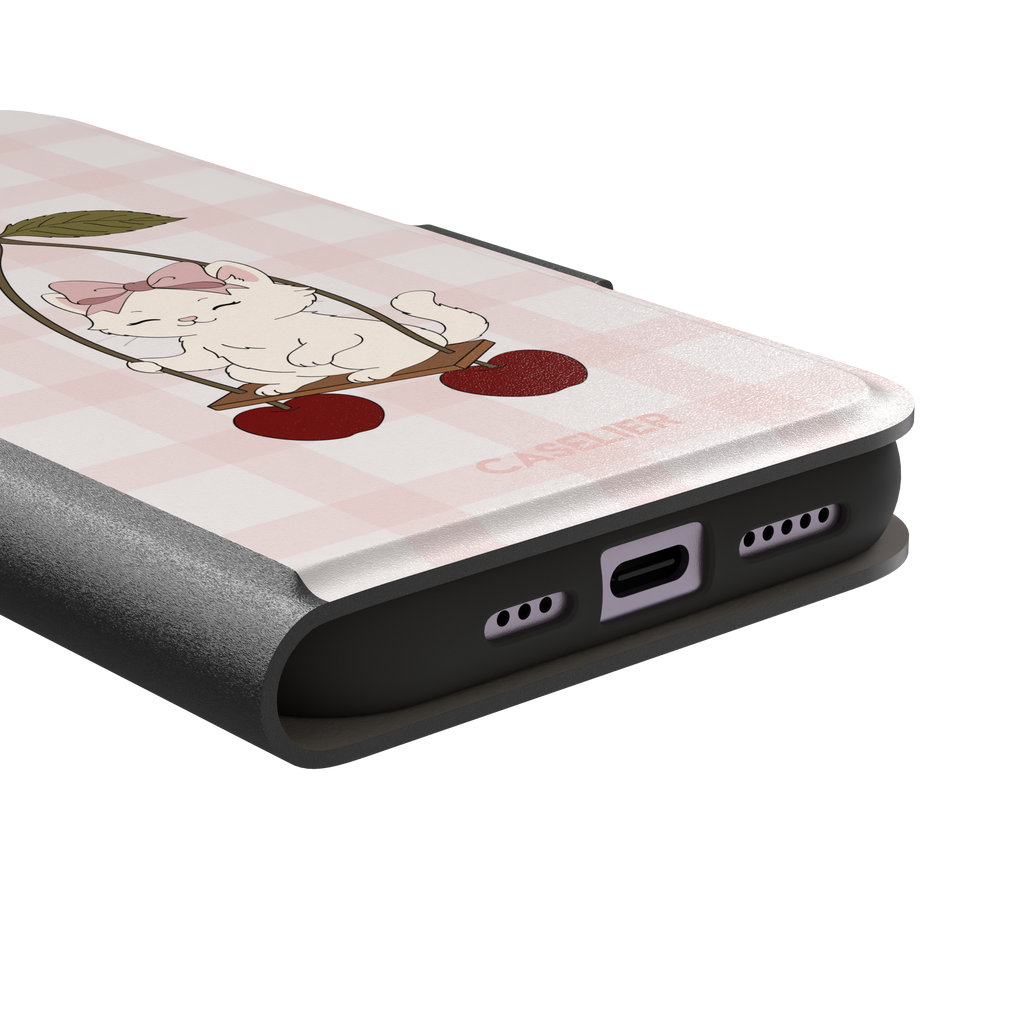 Cherry Swing phone case featuring a white cartoon kitten with a pink bow sitting on a cherry-suspended swing over a blush pink gingham background, phone case by Caselier — wallet case, charging port detail