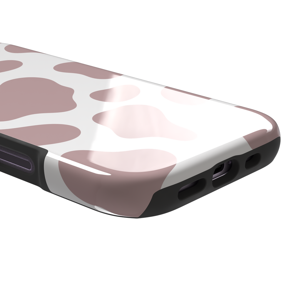 Cow print phone case in dusty rose pink and white with large soft-edged spots across the full back, phone case by Caselier — tough case, charging port detail