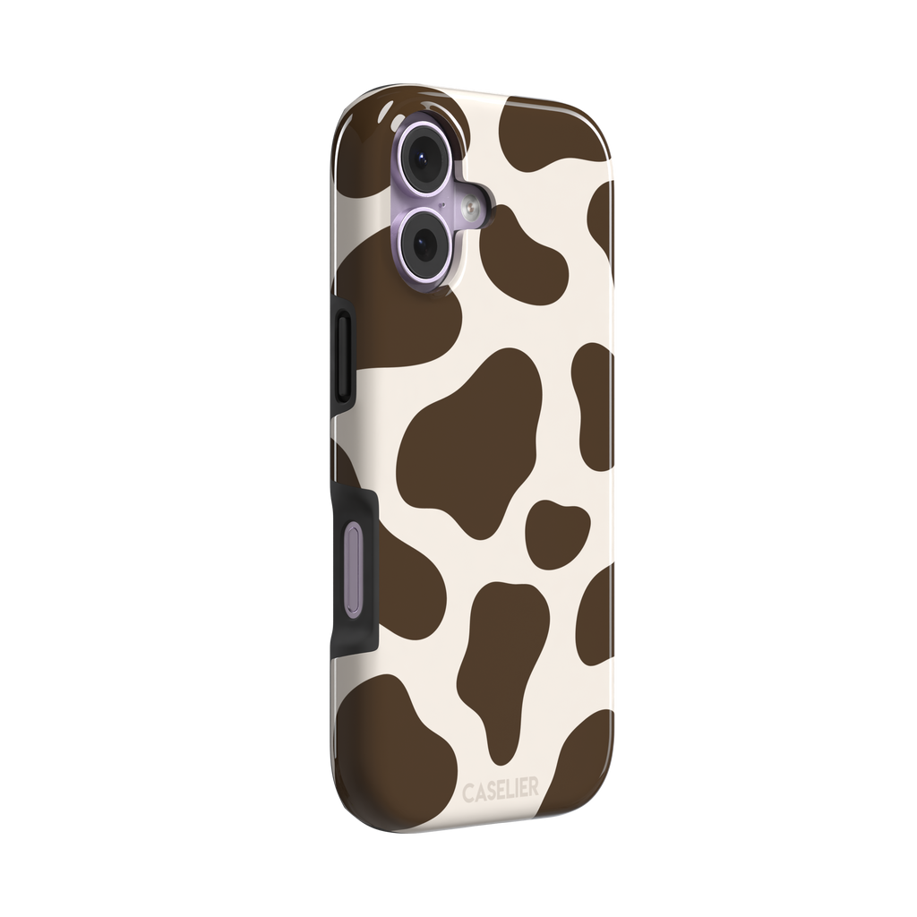 Cow print phone case in deep brown and cream with large irregular spots covering the full back, phone case by Caselier — tough case, left view