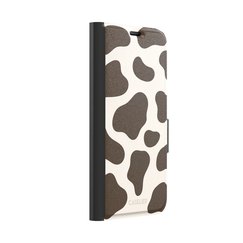 Cow print phone case in deep brown and cream with large irregular spots covering the full back, phone case by Caselier — wallet case, left view