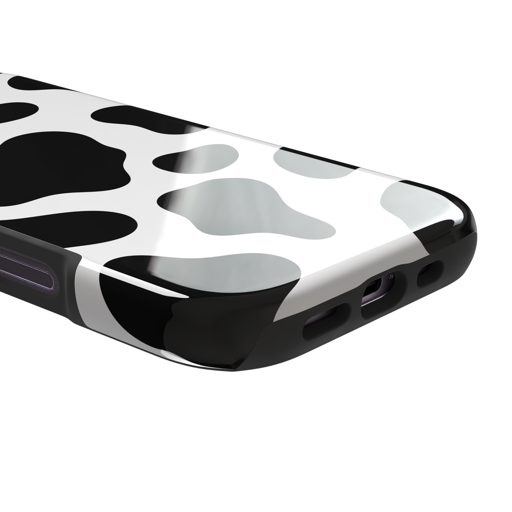 Cow print phone case in black and white with bold oversized spots on a clean white background, phone case by Caselier — tough case, charging port detail