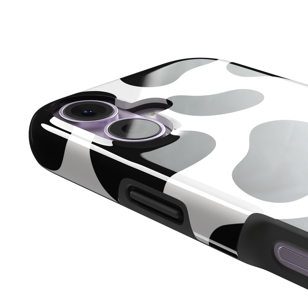 Cow print phone case in black and white with bold oversized spots on a clean white background, phone case by Caselier — tough case, volume buttons detail