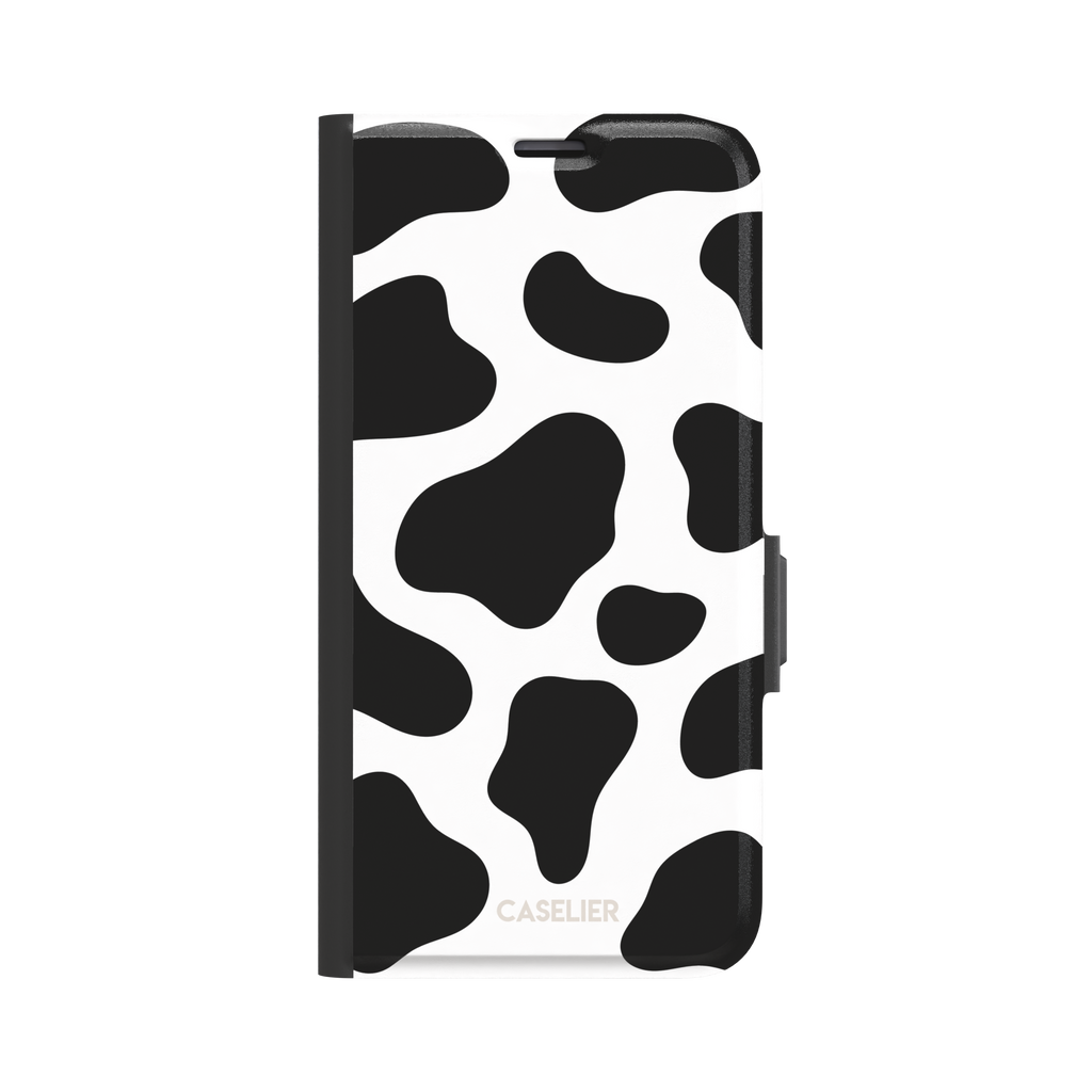 Cow print phone case in black and white with bold oversized spots on a clean white background, phone case by Caselier — wallet case, front view