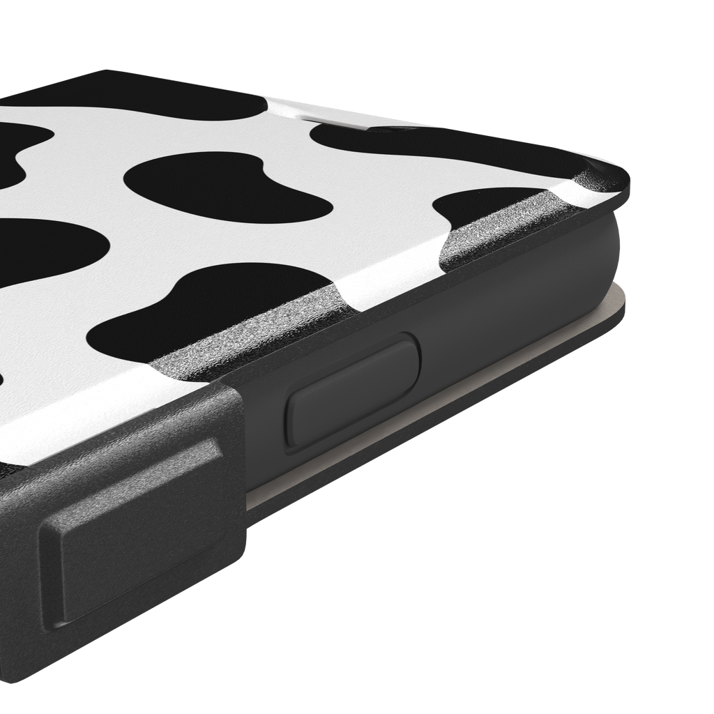 Cow print phone case in black and white with bold oversized spots on a clean white background, phone case by Caselier — wallet case, volume buttons detail