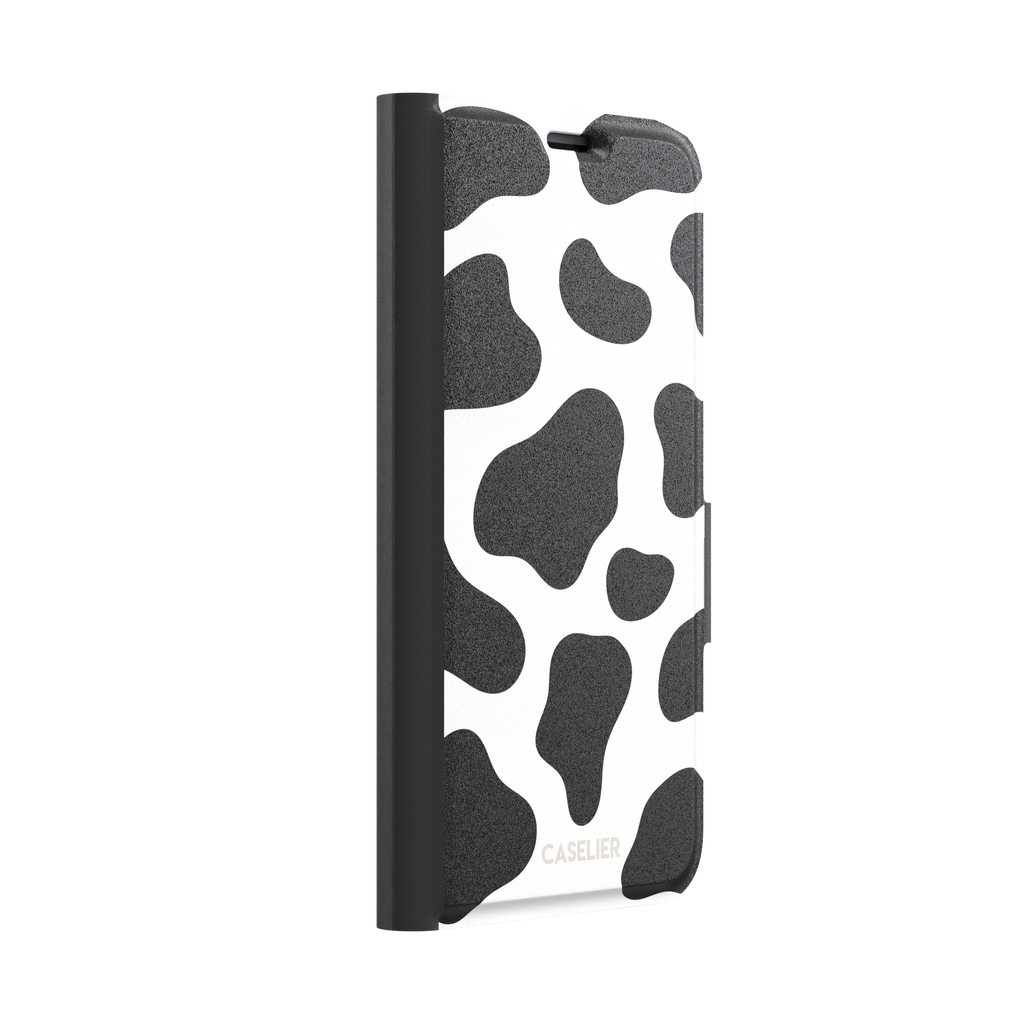 Cow print phone case in black and white with bold oversized spots on a clean white background, phone case by Caselier — wallet case, left view