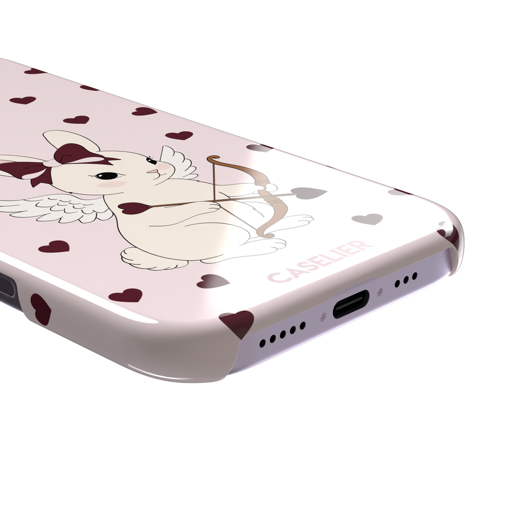 Blush pink phone case featuring a winged white cupid bunny with a burgundy bow and arrow surrounded by dark red hearts, phone case by Caselier — snap case, charging port detail