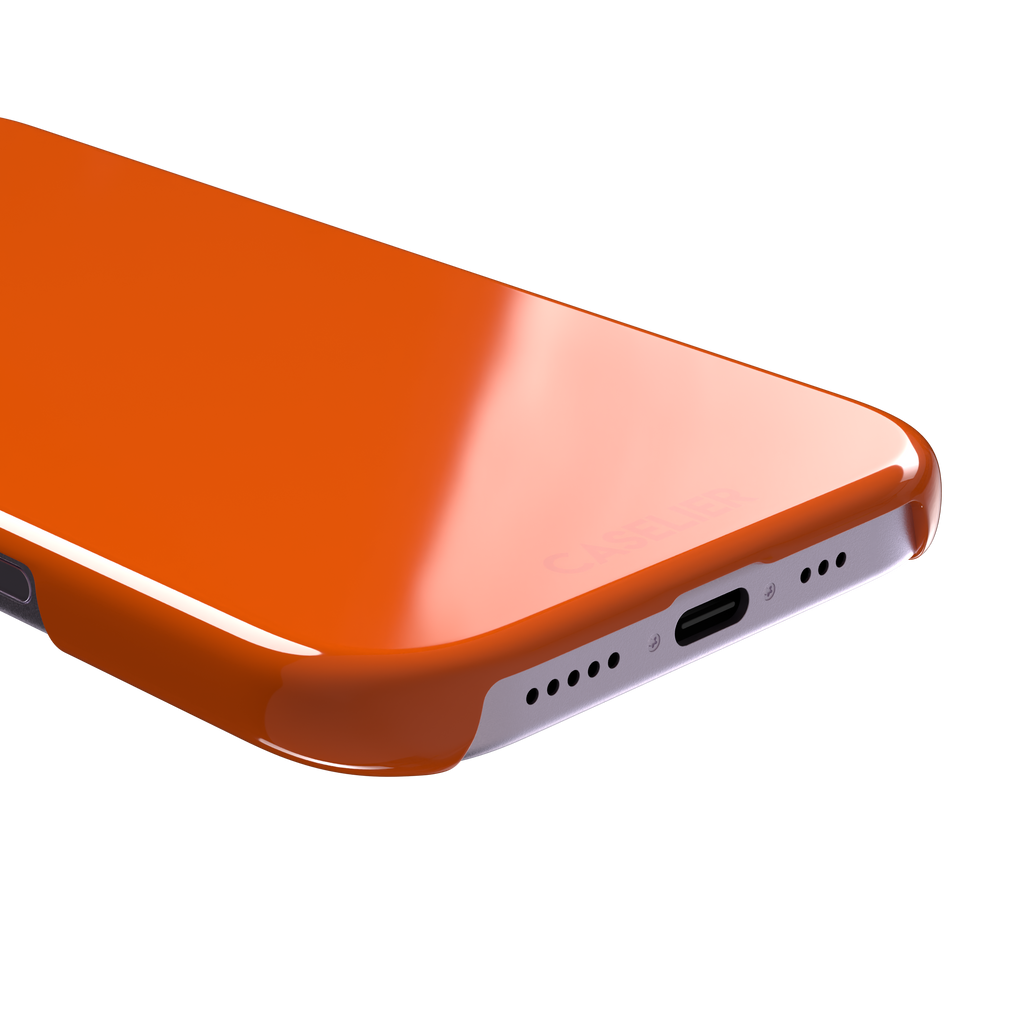 Bold vivid orange solid-color phone case, slightly zoomed front view on iPhone, phone case by Caselier — snap case, charging port detail