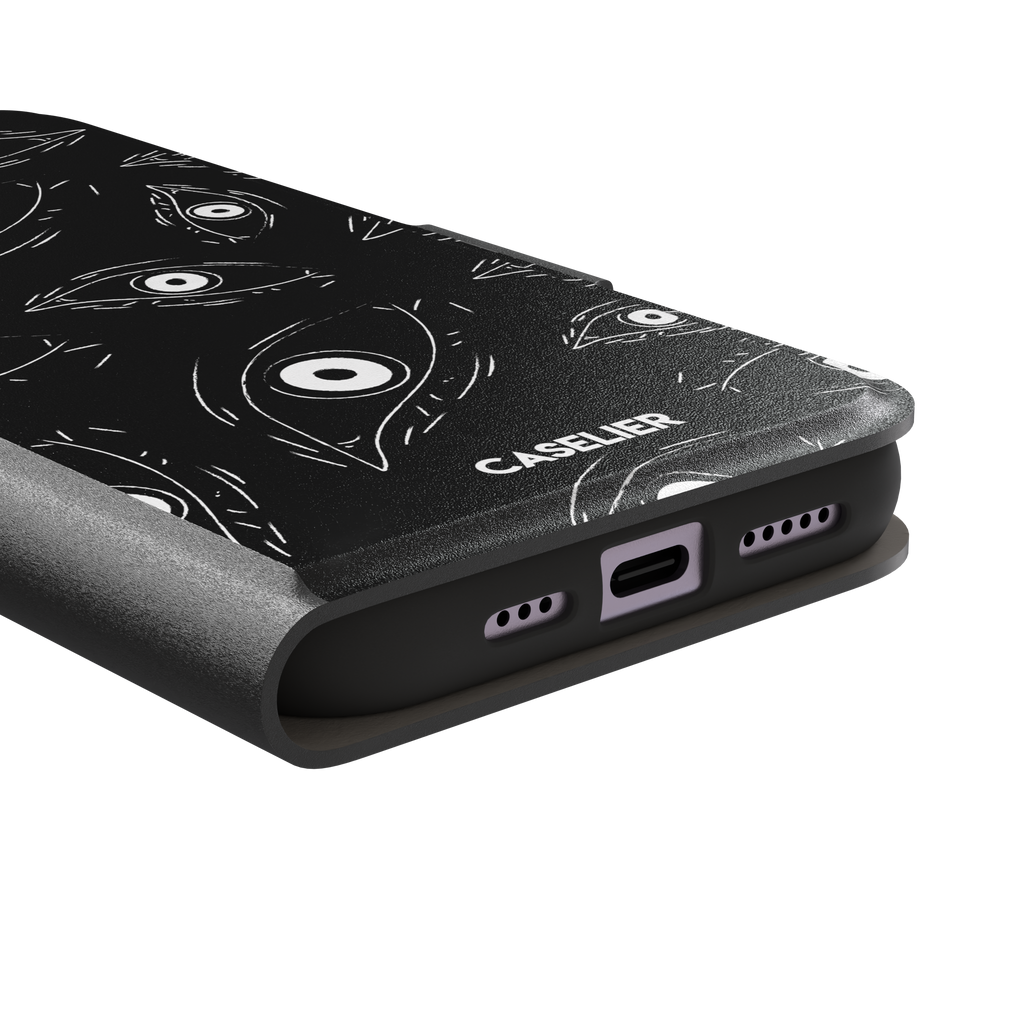 Paranoia phone case in black with all-over white hand-drawn staring eyes and sharp angular lashes, phone case by Caselier — wallet case, charging port detail