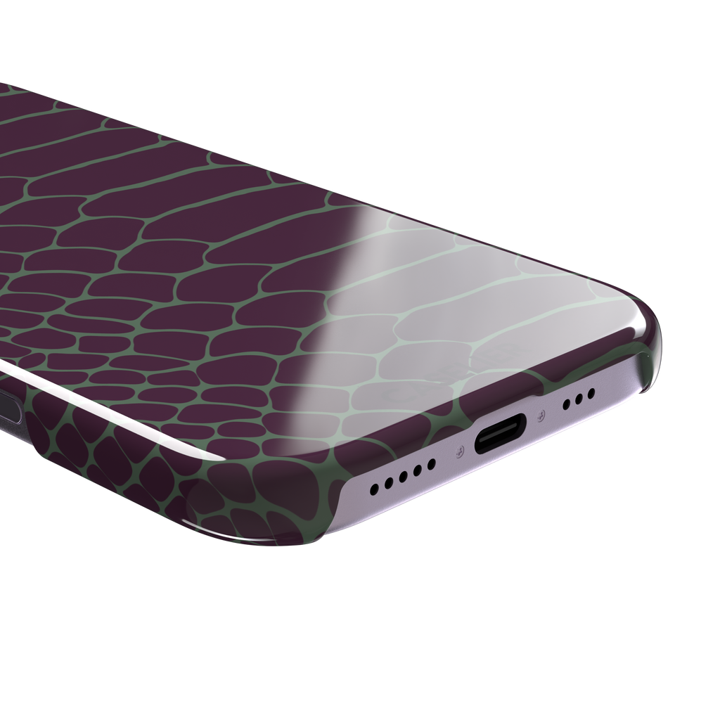 Deep plum and sage green snakeskin print phone case with muted green scale outlines on a rich purple base, phone case by Caselier — snap case, charging port detail