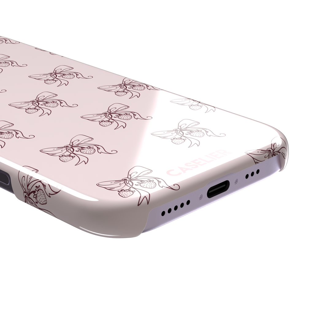 Strawberry Bows phone case in blush pink with an all-over pattern of line-drawn ribbon bows and hanging strawberries, phone case by Caselier — snap case, charging port detail