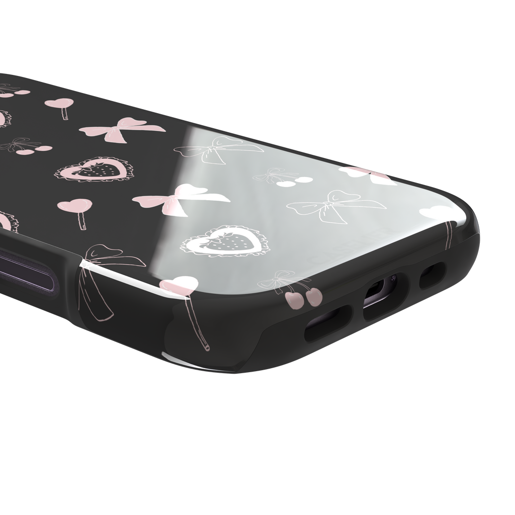 Sweetness Overload phone case in dark charcoal grey with pink bows, cherries, heart lollipops and frilled strawberry heart illustrations — tough case, charging port detail