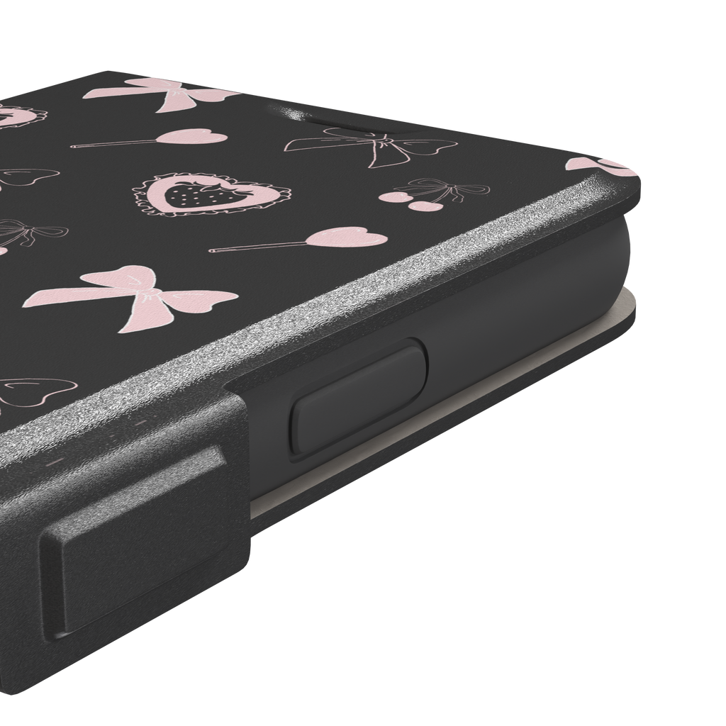 Sweetness Overload phone case in dark charcoal grey with pink bows, cherries, heart lollipops and frilled strawberry heart illustrations — wallet case, volume buttons detail