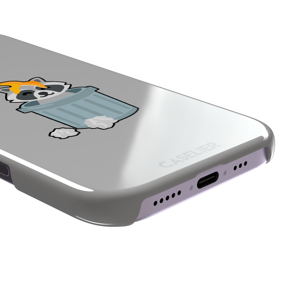 Grey phone case featuring a cute cartoon raccoon sitting inside a metal trash can with an orange food scrap on its head and crumpled paper on the ground, phone case by Caselier — snap case, charging port detail