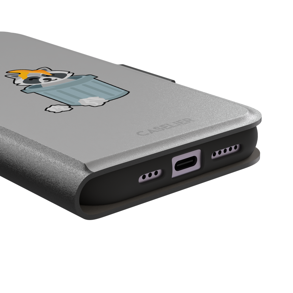 Grey phone case featuring a cute cartoon raccoon sitting inside a metal trash can with an orange food scrap on its head and crumpled paper on the ground, phone case by Caselier — wallet case, charging port detail